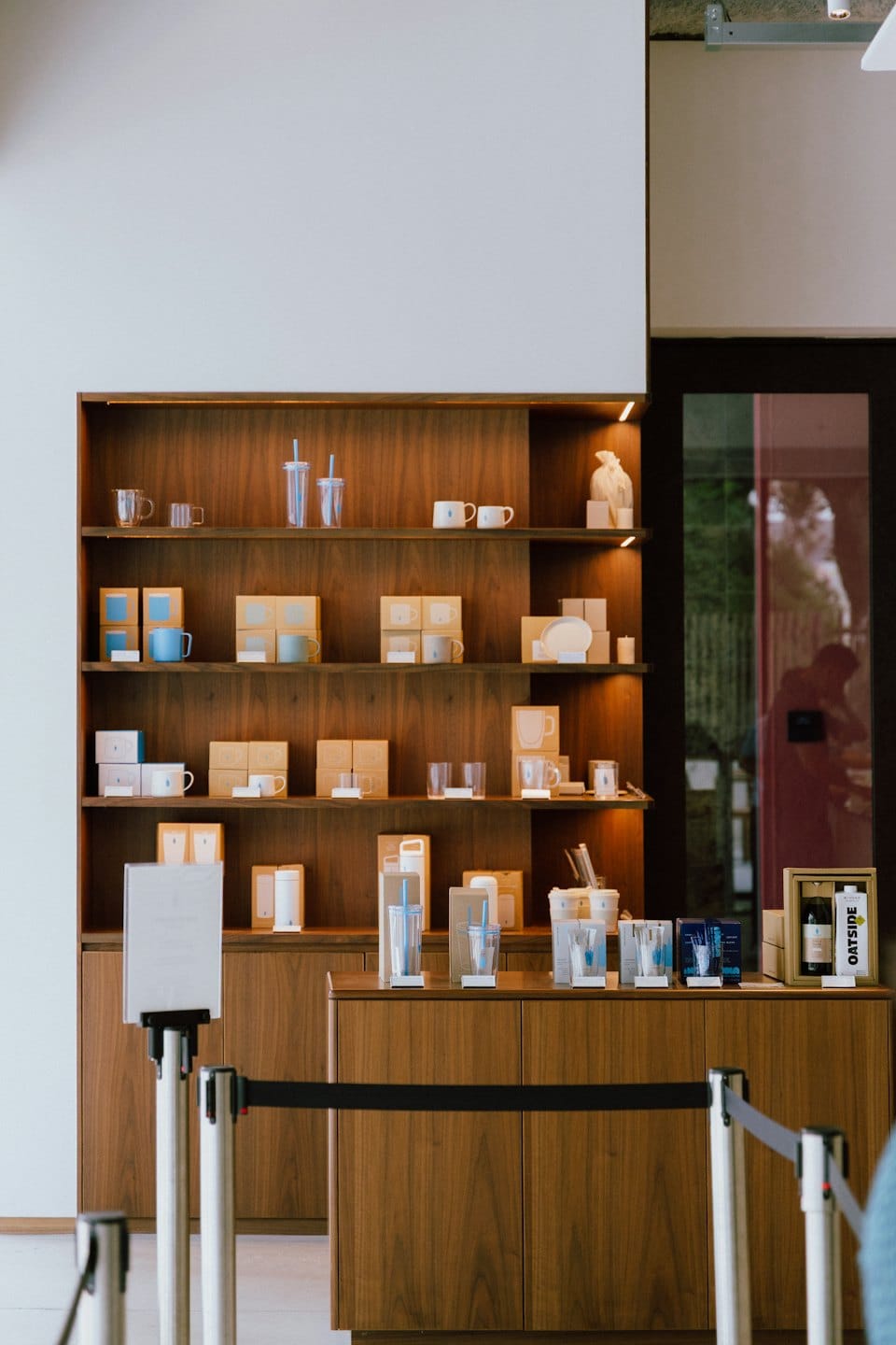 Retail display of cups, tumblers, and boxed items on wooden shelves.